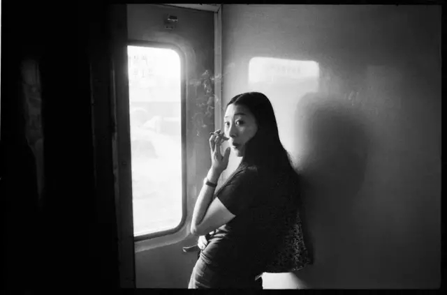 1998年,从北京开往哈尔滨的列车上,车窗旁抽烟的女青年.