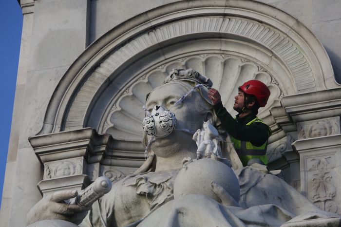 Greenpeace activists fit The Victoria Memorial in front of Buckingham Palace with an emergency face mask (photo by John Cobb)