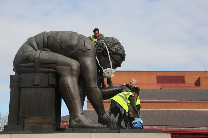 Greenpeace activists fit a statue of Isaac Newton at The British Library with an emergency face mask (photo by John Cobb)
