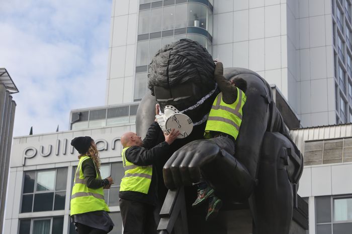Greenpeace activists fit a statue of Isaac Newton at The British Library with an emergency face mask (photo by John Cobb)