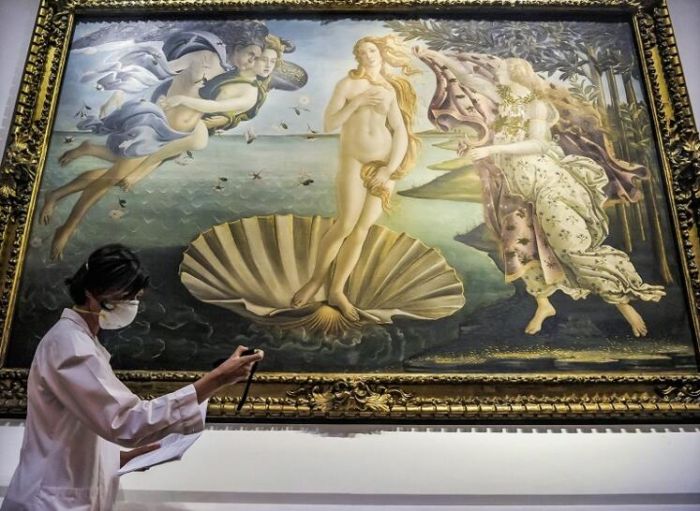 乌菲兹美术馆建于1560年，馆藏以美第奇家族收藏为基础，是佛罗伦萨历史最悠久的美术馆。受新冠疫情蔓延影响，意大利全境博物馆已关闭超过1个月，预计从5月18日起乌菲兹美术馆将重新开放。图为乌菲兹美术馆闭馆期间，一名修复专家正在检查波提切利经典画作《维纳斯的诞生》。（摄影师：Laura Lezza）