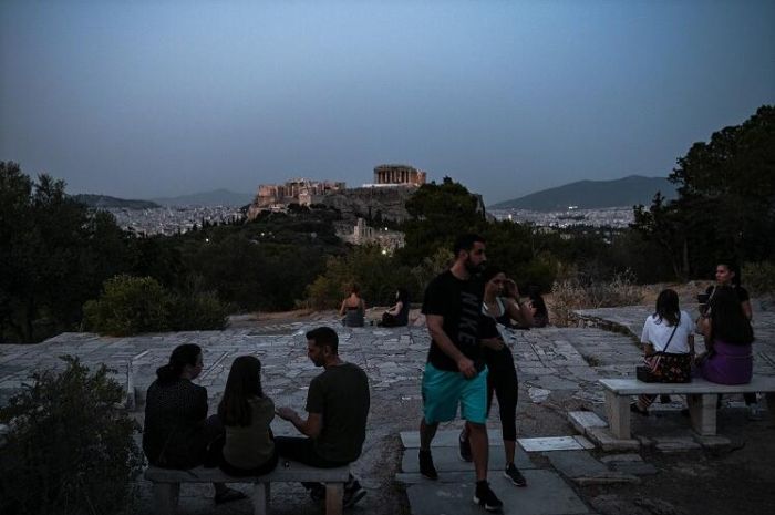 5月18日，希腊超过200个考古遗址重新开放，包括雅典卫城 、古奥林匹亚遗址等。希腊政府呼吁欧盟制定统一的旅游检疫标准，使欧洲国家解禁后能重启国际旅行。图为人们在高处眺望帕特农神庙。（摄影师：Aris Messinis）